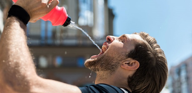 tired youthful bearded sportsman refreshing while training outside