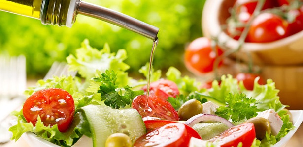 olive oil pouring into bowl of salad