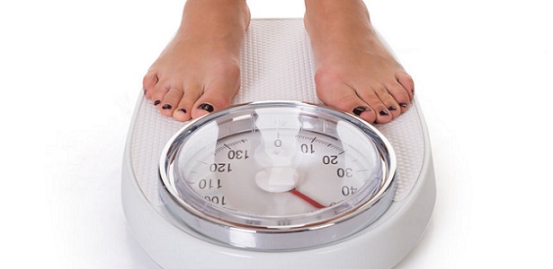 low section of woman standing on weighing scale over white background