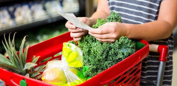 woman with red basket holding list in supermarket